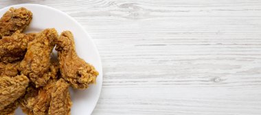 Beyaz ahşap artalan üzerinde yuvarlak beyaz plaka üzerinde tavuk kanatları