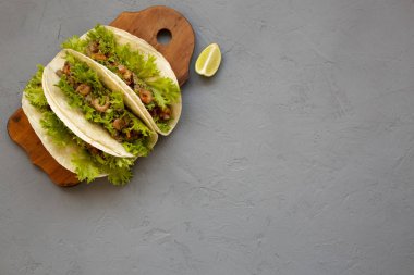 Üst görünüm, gri bir arka plan müziği üzerinde rustik ahşap tahta üzerinde karides Taco