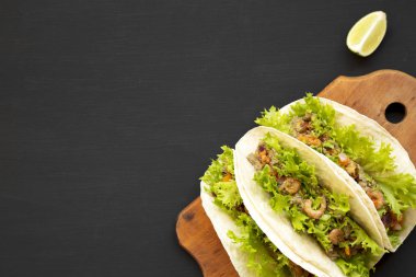 Siyah bir arka planda rustik ahşap tahta üzerinde karides Taco, üst