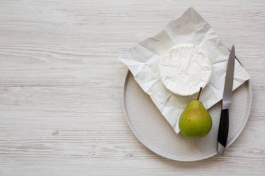 Üst görünüm, kağıt üzerinde Camembert peynir, bir plaka üzerinde taze armut. Gıda