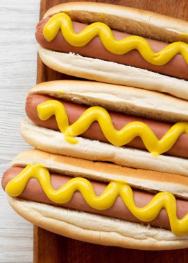 Beyaz bir rustik ahşap tahta üzerinde sarı hardal ile sıcak köpek 