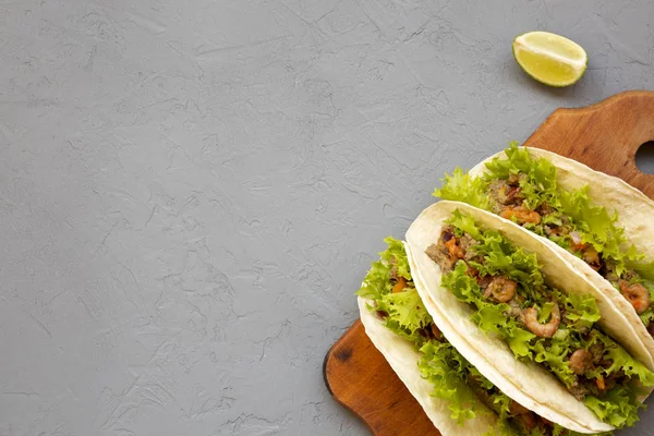 Tacos de camarão em uma tábua de madeira rústica em um fundo cinza, topo — Fotografia de Stock