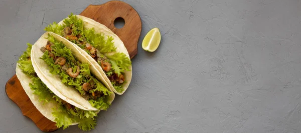 Tacos de camarão em uma tábua de madeira rústica em um fundo cinza. Plano — Fotografia de Stock