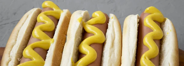 Hausgemachte leckere Hot Dogs mit gelbem Senf auf einem rustikalen Holztisch — Stockfoto