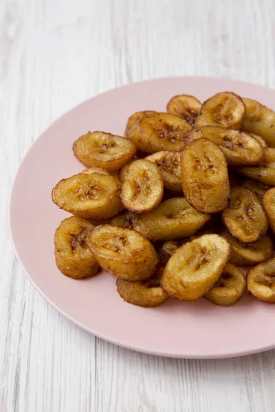 Plantains frits faits maison sur une assiette rose sur une surfa en bois blanc — Photo