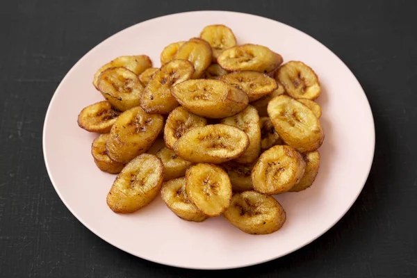 Bananas fritas caseiras em uma placa rosa em uma superfície preta, baixa — Fotografia de Stock