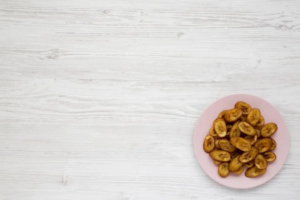 Plátanos fritos hechos en casa en un plato rosa sobre respaldo de madera blanca — Foto de Stock
