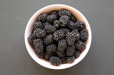 Siyah arka plan üzerinde pembe bir kase böğürtlen, üst görünüm. Toplam