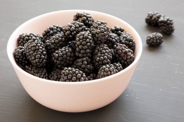 Siyah bir arka planda pembe bir kase içinde böğürtlen, yan görünüm. Su