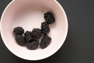 Siyah bir arka planda pembe bir kase böğürtlen, üst görünüm. Toplam