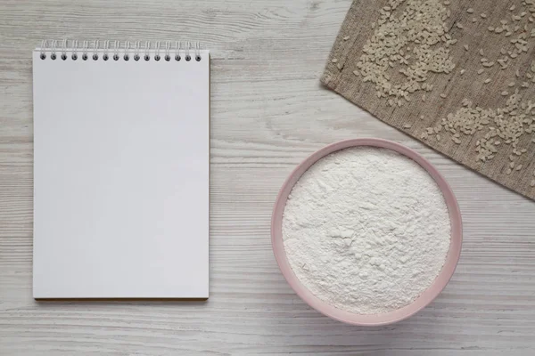 Gluten vrije rijstmeel in een roze kom, blanco Kladblok op een witte — Stockfoto