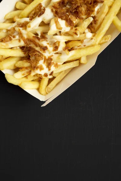French fries with cheese sauce and fried onion in a paper box on — Stock Photo, Image