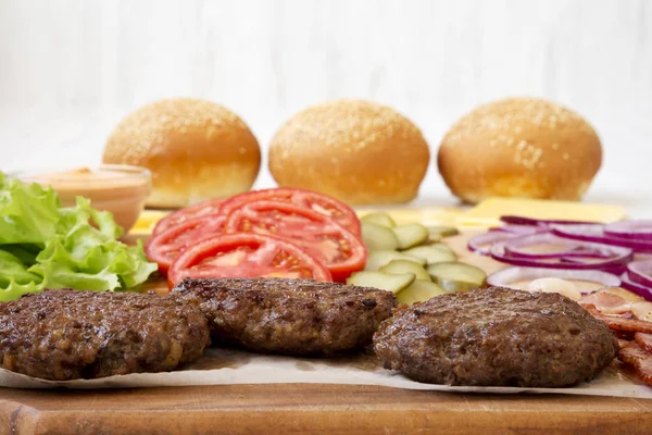 Burger ingredients on a white wooden background, side view. Clos