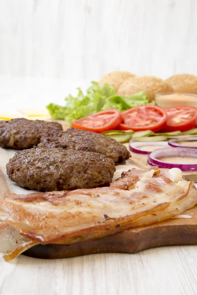 Burger ingredients on a white wooden table, side view. Close-up. — Stock Photo, Image