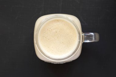 Siyah bir yüzeyde bir cam kavanozda fıstık ezmesi muz Smoothie,