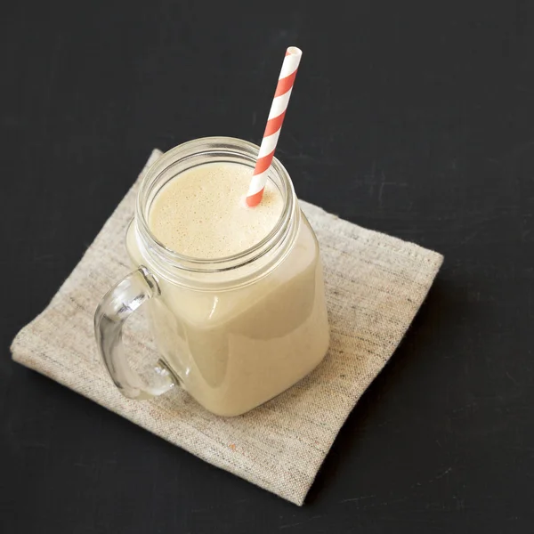 Erdnussbutter-Bananen-Smoothie im Glas auf schwarzem Hintergrund — Stockfoto