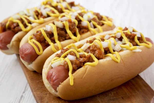 Homemade Detroit style chili dog on a rustic wooden board on a w