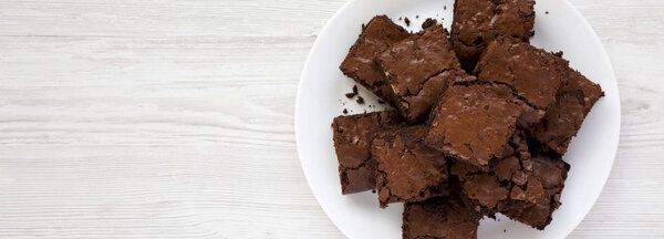 Домашние шоколадные брауни на белой тарелке на белом деревянном b
