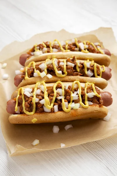 Homemade Detroit Style chili dog on parchment, side view. Closeu