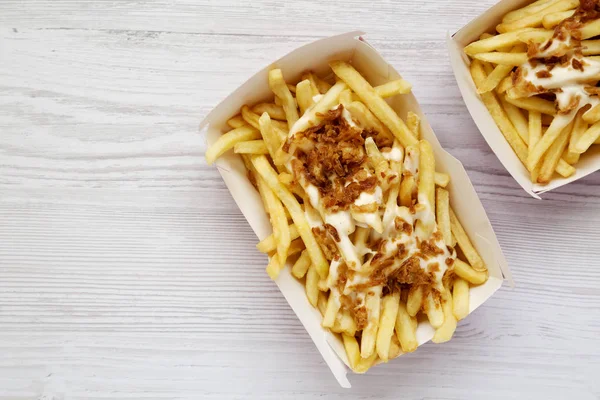 French fries with cheese sauce and fried onion in paper boxes on — Stock Photo, Image