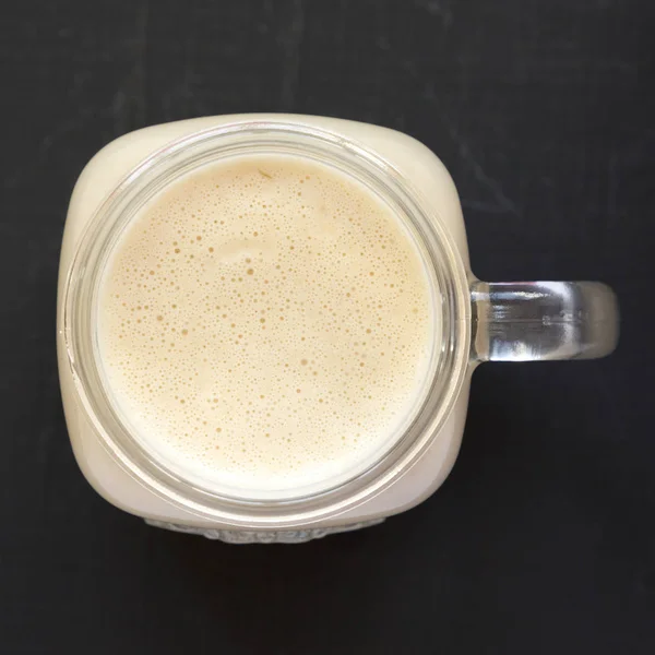 Peanut butter banana smoothie in a glass jar on a black backgrou — Stock Photo, Image