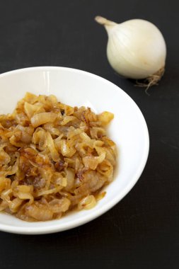 Siyah bir backgrou üzerinde beyaz bir tabak üzerinde ev yapımı karamelize soğan