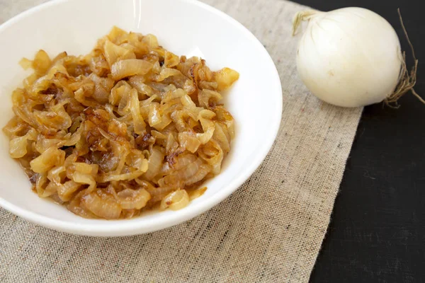 Homemade caramelized onions on a white plate on a black surface,