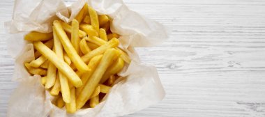 Beyaz ahşap arka plan üzerinde bir kağıt kutusunda patates kızartması, üst vi