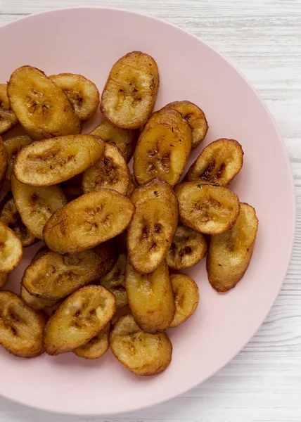 Plantains frits faits maison sur une assiette rose sur un fond en bois blanc — Photo