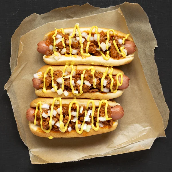 Homemade Detroit style chili dog on a black background, overhead