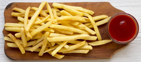 French fries with sauce on a rustic wooden board on a white wood — Stock Photo, Image