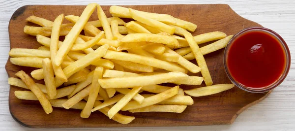 Frites à la sauce sur une planche de bois rustique sur un bois blanc — Photo