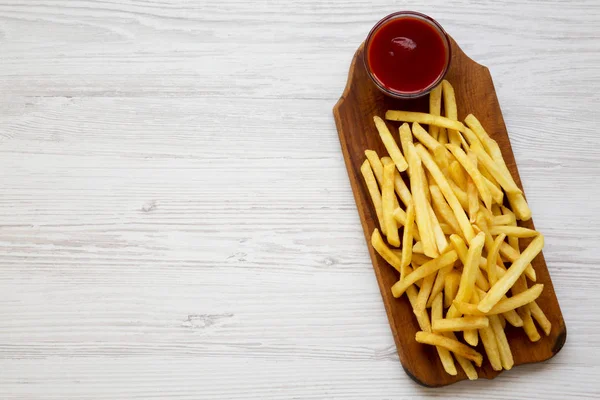 French fries with sauce on a rustic wooden board on a white wood — Stock Photo, Image