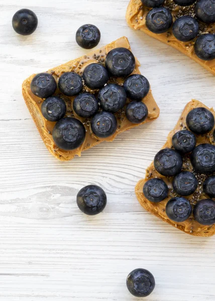 Vegan rostat bröd med jordnötssmör, blåbär och Chia frön på en — Stockfoto