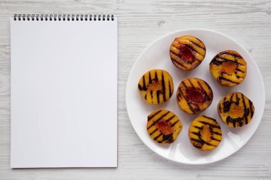 Beyaz tabakta ev yapımı ızgara şeftali, boş not defteri wh