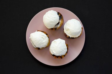 Pembe bir tabak üzerinde vanilyalı dondurma ile ev yapımı ızgara şeftali 