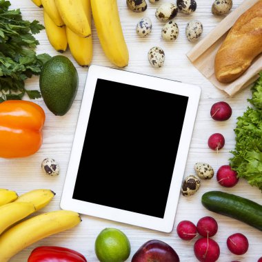 Beyaz bir woo üzerinde merkezinde tablet ile çiğ sağlıklı gıda seti