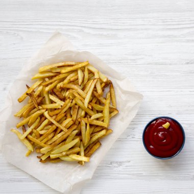 Beyaz ahşap yüzeyüzerinde ketçap ile ev yapımı patates kızartması,