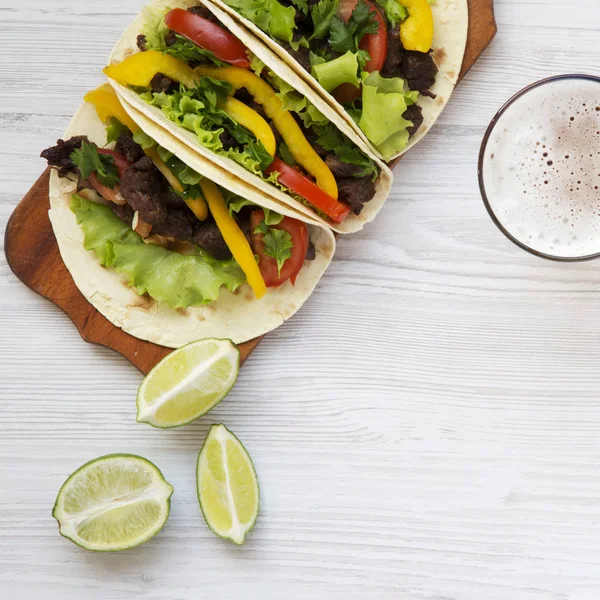 Rindfleisch-Tacos mit Salat, Tomaten und Bier auf weißem Holzbackgro — Stockfoto