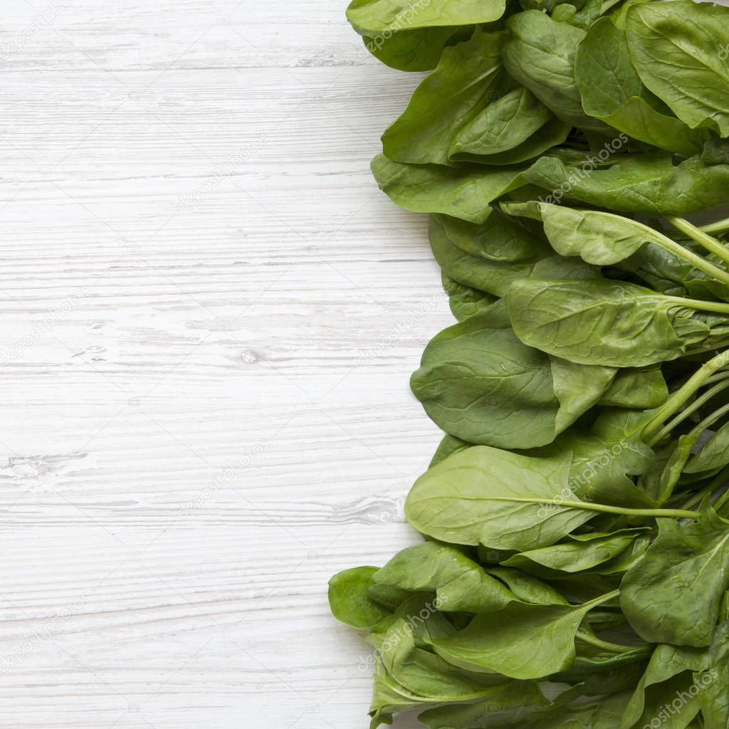 Washed fresh spinach leaves on a white wooden table, top view. F