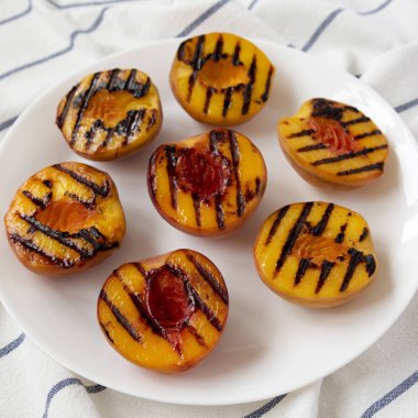 Beyaz bir tabak, düşük açı görünümü üzerinde ev yapımı ızgara şeftali. Yakın