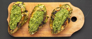 Siyah bir yüzey üzerinde rustik ahşap tahta üzerinde ızgara chimichurri tavuk göğsü, üst görünümü. Düz yatıyordu, yukarıdan, yukarıdan. 