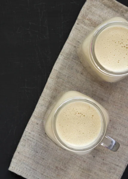 Peanut butter banana smoothie in glass jar mugs on a black surfa — Stok Foto
