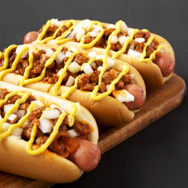 Homemade Detroit style chili dog on a rustic wooden board on a b