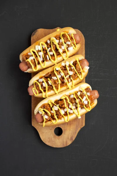Homemade Detroit style chili dog on a rustic wooden board on a b