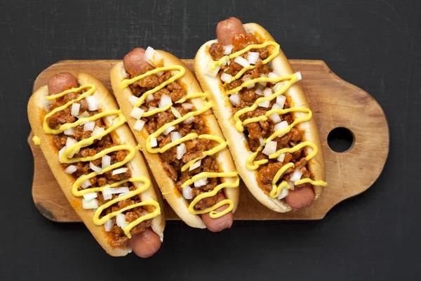 Homemade Detroit style chili dog on a rustic wooden board on a b