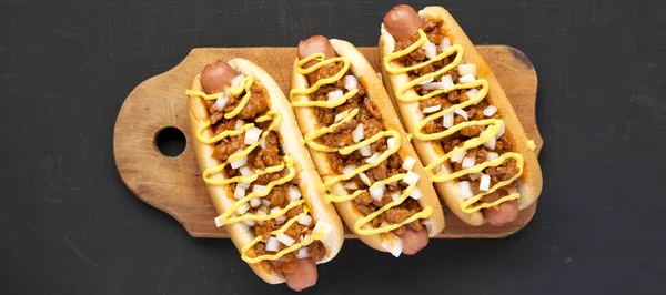 Homemade Detroit style chili dog on a rustic wooden board on a b