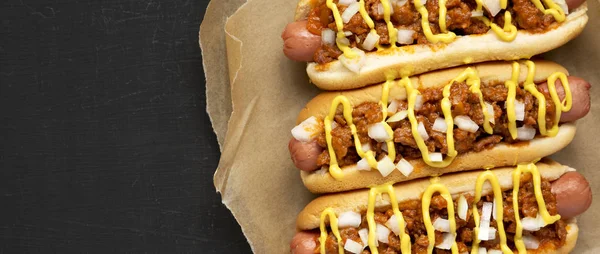 Homemade Detroit style chili dog on a black background, top view