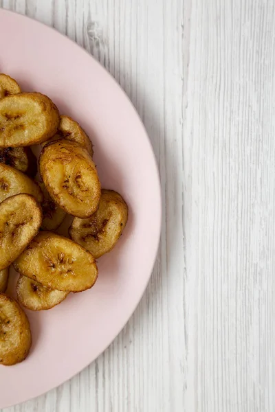 Plantains frits faits maison sur une assiette rose sur une surfa en bois blanc — Photo