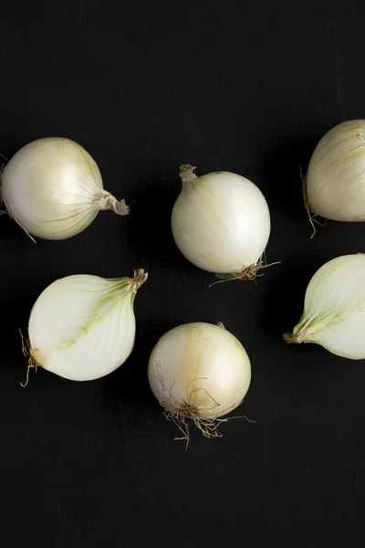 Raw white onions on a black background, top view. Flat lay, over
